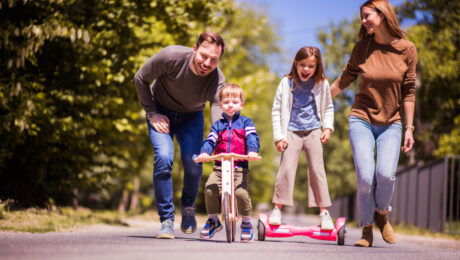 family on a street with kids on hoverboard and scooter